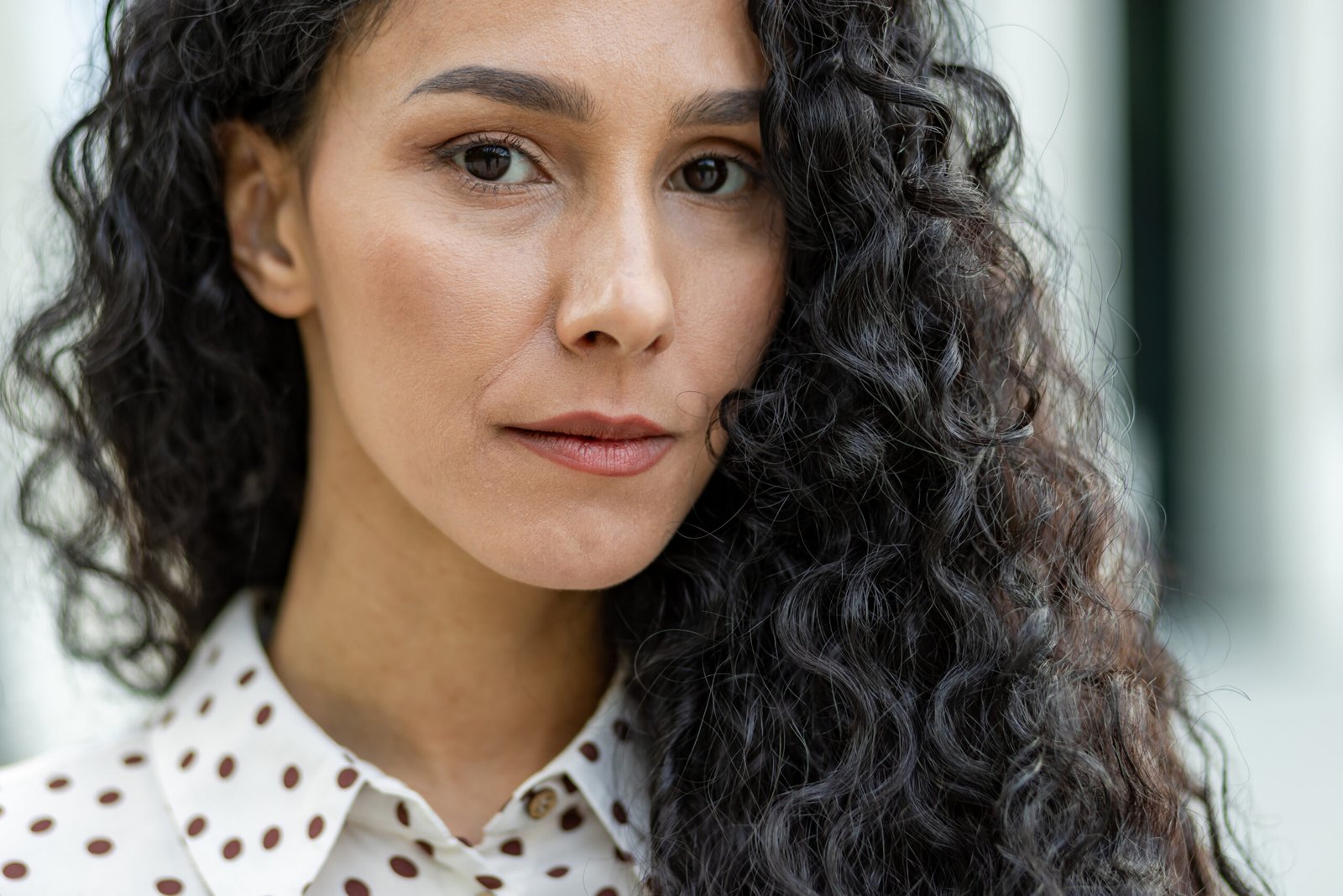 elegant woman with curly hair in a polka dot blous 2024 03 05 23 33 04 utc scaled